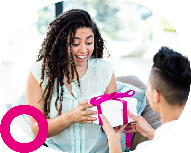A joyful woman receiving a gift from a man outdoors.