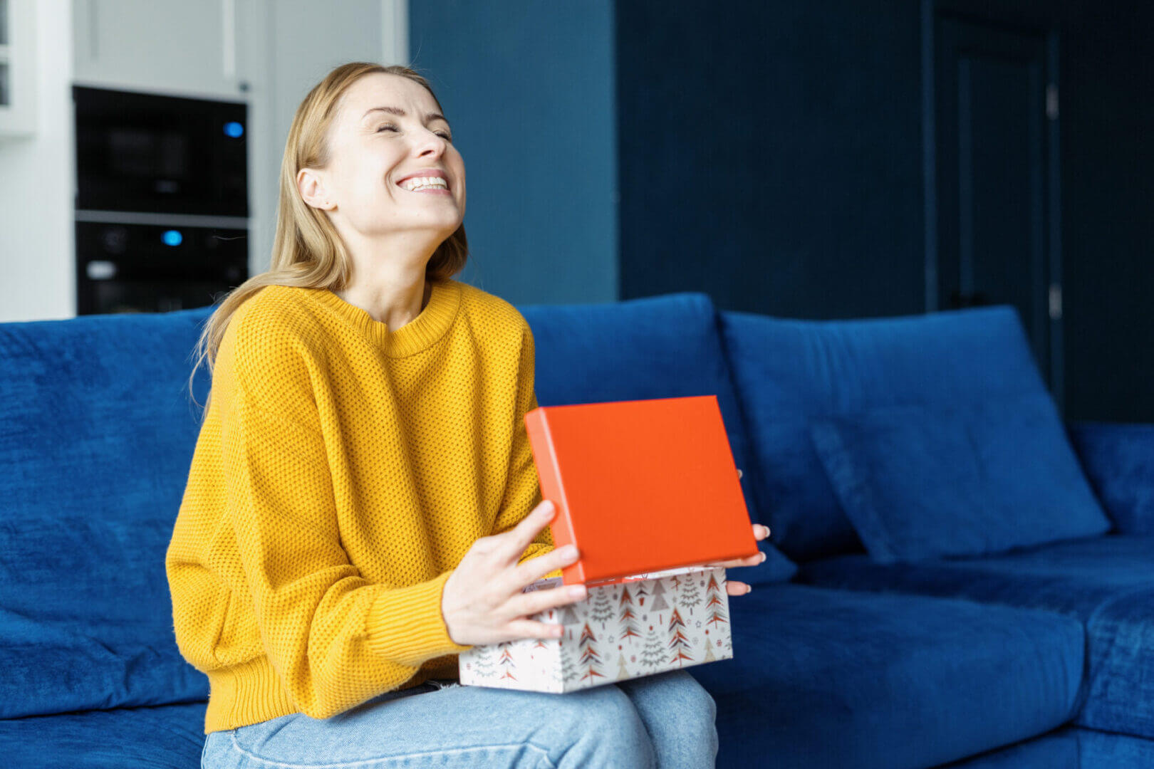 A joyful woman holding a gift box with a red lid.